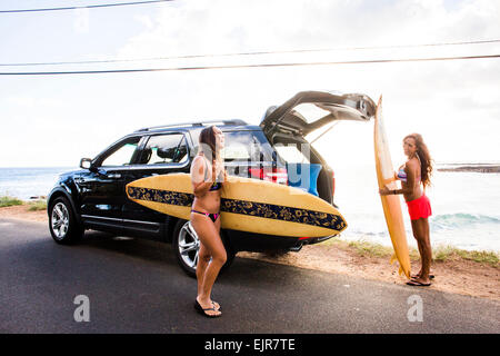 Surfer, die Entladung Surfbretter aus Auto in der Nähe von Strand Stockfoto