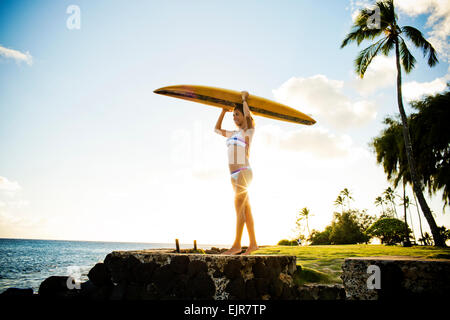 Surfer mit Surfbrett über ihren Kopf in der Nähe von Meer Stockfoto