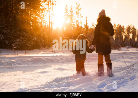Mutter und Sohn gehen auf verschneiten Waldlichtung Stockfoto