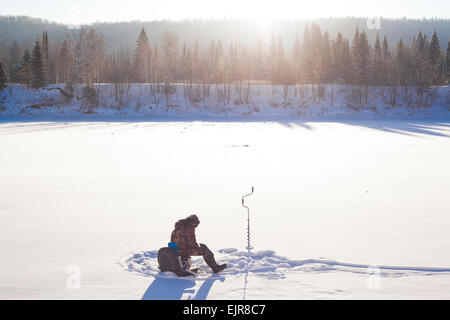 Mari Mann Eisfischen in schneebedecktes Feld Stockfoto