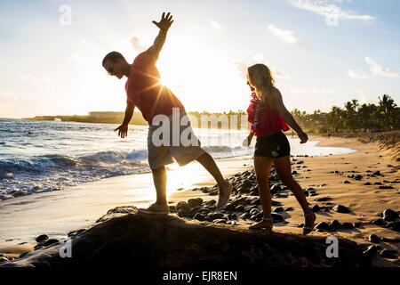 Paar auf Felsen am Strand spielen Stockfoto