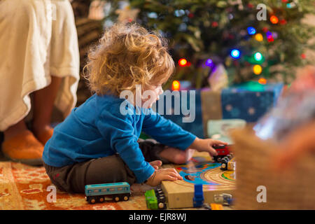 Kaukasischen Jungen spielen mit Spielzeug unter dem Weihnachtsbaum Stockfoto