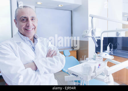 Hispanische Zahnarzt lächelnd in der Nähe von Stuhl im Büro Stockfoto