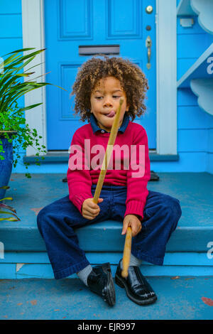 Pacific Islander jungen mit Drumsticks sitzen am vorderen stoop Stockfoto