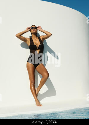 Gemischte Rassen Frau im Badeanzug mit Sonnenbrille in der Nähe von Schwimmbad Stockfoto
