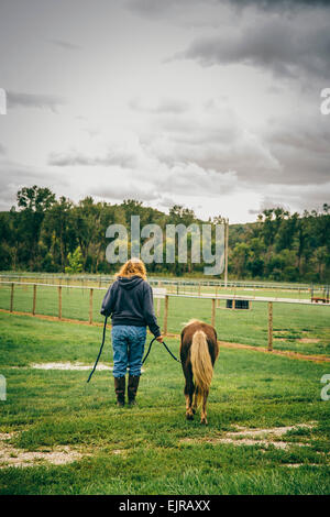 Kaukasische Frau zu Fuß Miniaturpferd auf ranch Stockfoto