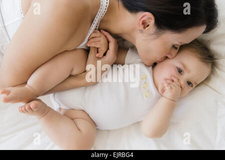 Draufsicht der Mischlinge Mutter küssen Baby auf Bett Stockfoto