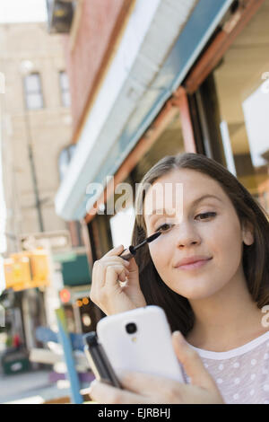 Kaukasische Frau beim Schminken in Handy-Kamera Stockfoto