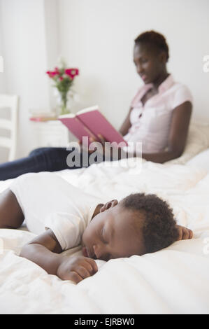 Schwarze Mutter lesen in der Nähe schlafen Baby boy Stockfoto