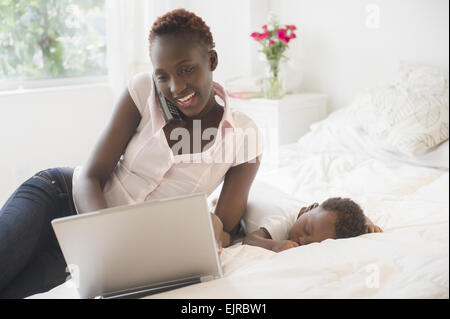 Schwarz mit Laptop in der Nähe schlafen Baby junge Mutter Stockfoto