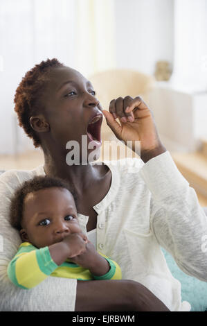 Gähnen schwarze Mutter hält Baby boy Stockfoto