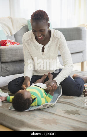 Schwarze Mutter ändern Windel Baby boy im Wohnzimmer Stockfoto