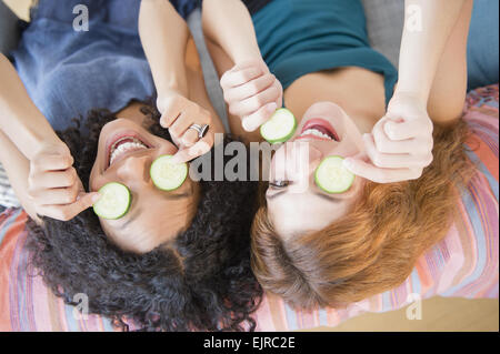 Frauen mit Gurkenscheiben über Augen Stockfoto