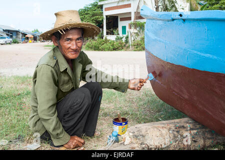 Fischerdorf - Lifestyle - Kep, Kambodscha, Asien. Ein Mann, der sein Boot Malerei. Stockfoto