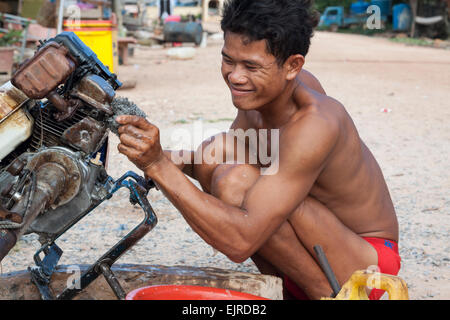 Fischerdorf - Lebensstil, Kep, Kambodscha. Ein junger Mann Reinigung Bootsmotor. Stockfoto