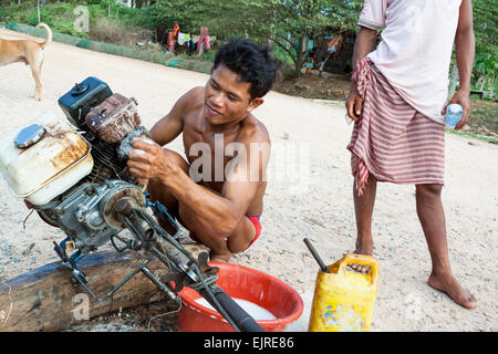 Fischerdorf - Lebensstil, Kep, Kambodscha. Ein junger Mann Reinigung Bootsmotor. Stockfoto