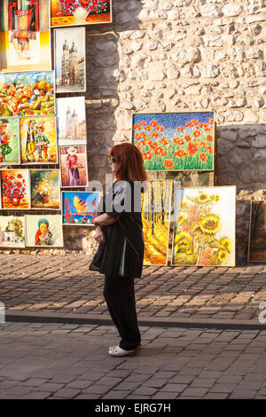 Frau, die Gemälde und Kunstwerke zum Verkauf im St. Florian-Tor, Krakau, Polen im September betrachtet - St. Florian-Tor, Florian-Tor, Brama Floriańska Stockfoto