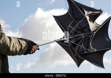 Mann hält einen Regenschirm in Sturm zwingen Winde Stockfoto