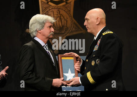 Stabschef der Armee, General Raymond T. Odierno die Medal Of Honor-Flagge an Dr. Terry Schwab, im Namen seines Vaters präsentiert, statt 1. Lt. Donald K. Schwab, einer der 24 Armee-Veteranen geehrt während der Valor 24 Halle der Helden Induktion Zeremonie im Pentagon, Washington D.C., 19. März 2014.  Herr Leroy Council Stockfoto