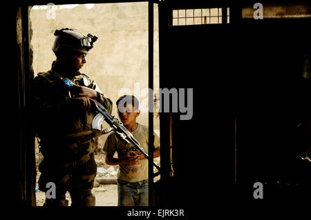 Ein irakischer Soldat schaut auf einen jungen, als er US-Soldaten Uhren und irakische Soldaten eines Gebäudes während einer gemeinsamen Patrouille in a., Irak, 19. Juni 2008 suchen. Die US-Soldaten sind 3rd Platoon, Bravo Company, 2. Brigade, 502. Infanterieregiment zugeordnet.  Staff Sgt Manuel J. Martinez Stockfoto