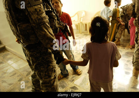 Ein irakische Kind hält sich an die Hand des Sgt. Michael Bearden, gebürtig aus Cartersville, Georgia, und anderen Kindern interagieren mit anderen Soldaten während eines Besuchs in der Al-Gowood-Waisenhaus in Kadhimiya, Irak, 30. Juli 2008. Die Soldaten sind Teil des Delta Company, 1. Bataillon, 502. Infanterieregiment, 101. US-Luftlandedivision. Air Force Staff Sgt Manuel J. Martinez Stockfoto