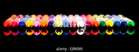 Ein Panorama-Format Bild mit verschiedenen farbigen Buntstiften auf eine glänzende schwarze Oberfläche reflektiert Stockfoto