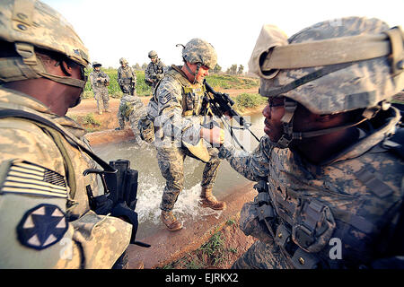 Soldaten helfen Air Force Staff Sgt Johnathon Krueger über einen Bewässerungskanal außerhalb Joint Base Balad, Irak, während der Operation Lewis und Clark Sept. 11. Betrieb-Lewis und Clark war eine gemeinsame Patrouille Sicherheitskräfte Flieger in die Luftwaffe Balads Außenumfang eingeführt wurden. Da Amerikaner Betrieb von Balad 2003 ihren, hat die Armee für Basis Sicherheit verantwortlich. 332. Expeditionary Kräfte Sicherheitsgruppe wird bald sein, dass die größte Sicherheitskräfte Einheit im Kampf eingesetzt, einem Luftwaffenstützpunkt seit Vietnam zu verteidigen. Sergeant Krueger ist der 332. Expeditionary Sicherheit F zugeordnet. Stockfoto