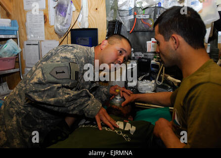 Sergeant Troy Galvan, 3rd Brigade Combat Team, 1. US-Infanteriedivision Medic und San Antonio, Texas stammende veranschaulicht einem ANA-Soldaten für ein Trauma Patientenatmung während eines 30-Tage-Kurs auf erste Hilfe zu sorgen. Sgt. Galvan sagt bis Ende der Ausbildung, die ANA-Soldaten sogar weiter fortgeschritten als Absolventinnen und Absolventen des Studiengangs bekämpfen Lebensretter werden. Stockfoto