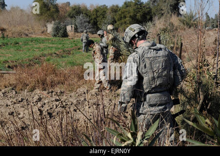 Soldaten aus 3. Bataillon, 29. Feldartillerie, 3rd Brigade Combat Team, 4. US-Infanteriedivision und irakische Soldaten führen Sie eine Waffen-Cache-Suche am 13. Januar in Bagdad, Irak. Stockfoto