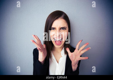 Böse Frau schreiend auf grauem Hintergrund. Blick in die Kamera Stockfoto