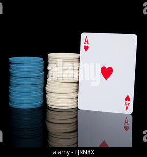 Zwei Stapel von blauen und weißen Poker chips mit einem Ass Herz-Karte auf eine glänzende schwarze Oberfläche reflektiert Stockfoto