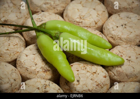 Drei grüne Tabasco Paprika sitzen auf einem Kork-Hintergrund Stockfoto