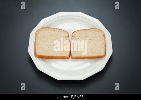 Zwei Scheiben Weißbrot stehen nebeneinander auf einem weißen Teller; der erste Schritt bei der Herstellung ein Erdnussbutter und Marmelade-sandwich Stockfoto