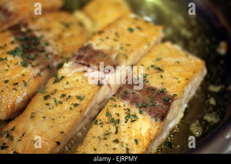 Lachs, getaucht in Pfanne anbraten Mehl, ist die Pfanne angebraten in Olivenöl mit Petersilie Flocken. Stockfoto