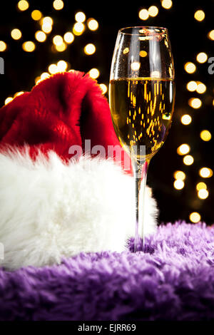 Ein Sektglas sitzt auf einer lila Fell-Oberfläche; weiße Bokeh im Hintergrund; perfekt für Weihnachten und Silvester; Roter Lippenstift m Stockfoto