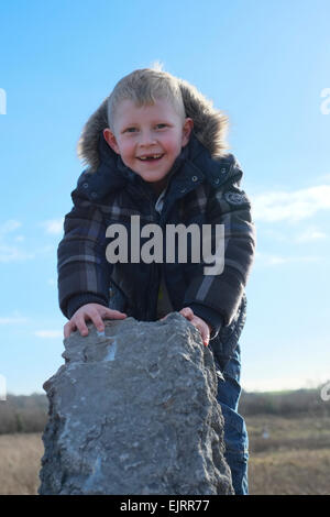 Lächelnde junge im Alter von sechs ohne vorderen Zähne auf Felsen draußen an der frischen Luft spielen. Stockfoto