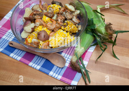 Eine Glasschüssel ist gefüllt mit Mais Maiskolben, rote Kartoffeln und Garnelen - eine klassische Garnelen kochen. Stockfoto