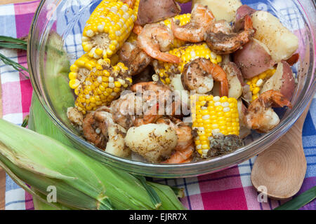 Eine Glasschüssel ist gefüllt mit Mais Maiskolben, rote Kartoffeln und Garnelen - eine klassische Garnelen kochen. Stockfoto