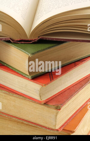 Alte Bücher von verschiedenen Farben werden gestapelt auf einander.  Die an der Spitze ist offen für die Seiten und die Wirbelsäule zu offenbaren. Stockfoto