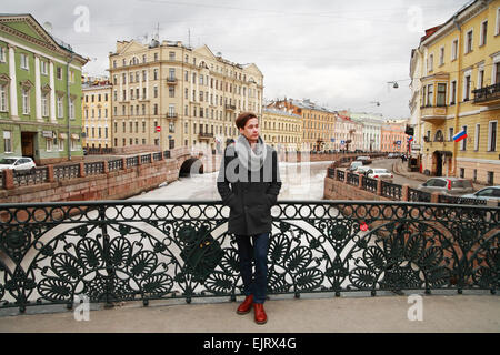 Junger Mann posiert in der Moyka Bahndamm in der Hintergrund-Architektur, St. Petersburg Stockfoto