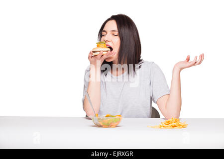 gesunde gegen Junk-Food-Konzept mit einer natürlichen Frau isoliert wogenden vor Obst essen und wählen Sie Pommes mit Hamburger, o Stockfoto