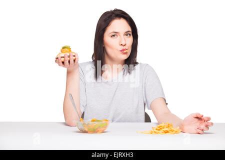 gesunde gegen Junk-Food-Konzept mit einer natürlichen Frau isoliert wogenden vor Obst essen und wählen Sie Pommes mit Hamburger, o Stockfoto