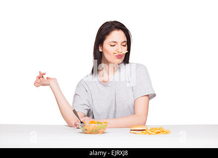 natürliche ausdrucksstarken Frau spielt mit Pommes frites, vor Junk-e- und gesund essen, isoliert auf weiss Stockfoto