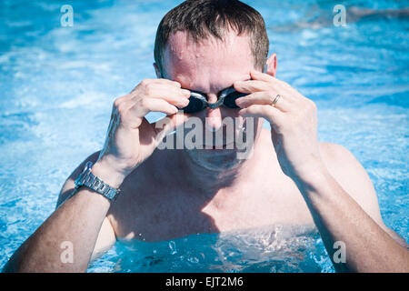 Mann im Schwimmbad eine Uhr zu tragen und Schwimmen Googles einstellen. Stockfoto