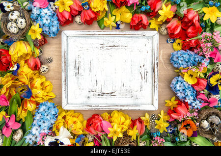 Ferien-Hintergrund mit Frühlingsblumen, Ostereier und weißen Schreibtisch aus Holz für Ihren Text. Vintage shabby chic Stil Stockfoto