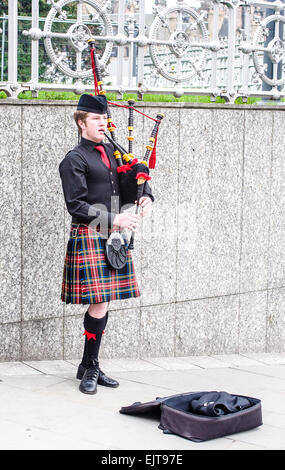 Ein junger Dudelsackspieler tragen traditionelle rote Tartan Kilt spielt für Spenden auf den Straßen von Edinburgh, Schottland. Stockfoto