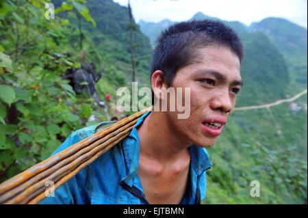 (150401)--DAHUA, 1. April 2015 (Xinhua)--ein Dorfbewohner trägt auf seinem Rücken im Nongwei Dorf dann Township im Südwesten Chinas autonome Region Guangxi Zhuang, 18. Juni 2014 Armierung.? Wegen des Mangels an Flachland bauen die meisten Familien in den westlichen Bergregionen der Dahua ihre Häuser auf Hügeln. In den Qibainong und dann der Dahua haben Menschen der Miao ethnische Gruppe in den Bergen etwa eintausend Jahre lang gelebt. Sie zählen auf die Anpflanzung von Hühneraugen für ihren Lebensunterhalt. Gestelzt dreistöckige Gebäude ist der traditionellen Architektur-Stil in den beiden Landkreisen. Menschen f Stockfoto