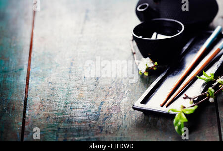 Chinesische Tee-Set, Stäbchen und Sakura Zweig am rustikalen Holztisch Stockfoto