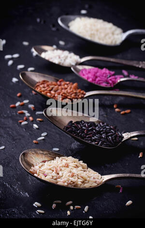 Reihe von ungewöhnlichen Reis in Vintage Löffel über dunkle Oberfläche. Stockfoto