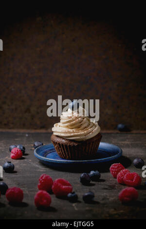 Schokolade Cupcake mit butter Kaffee Sahne und frische Beeren auf dunklem Hintergrund Stockfoto